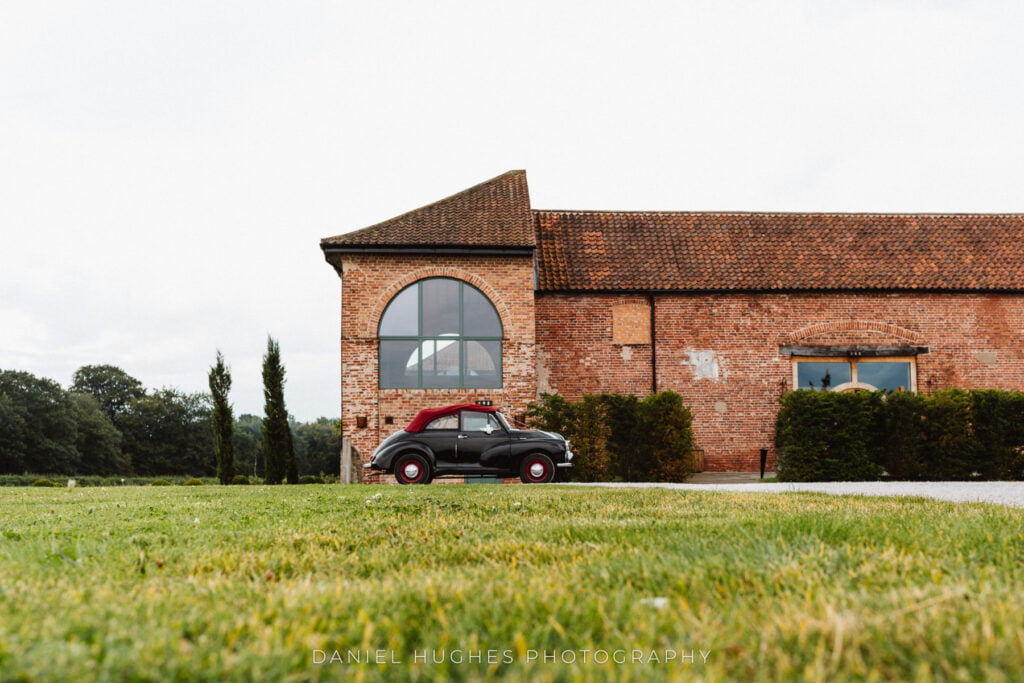 Low-angle shot of a vintage black car with a Red Soft top parked out in front of Hazel Gap Barn