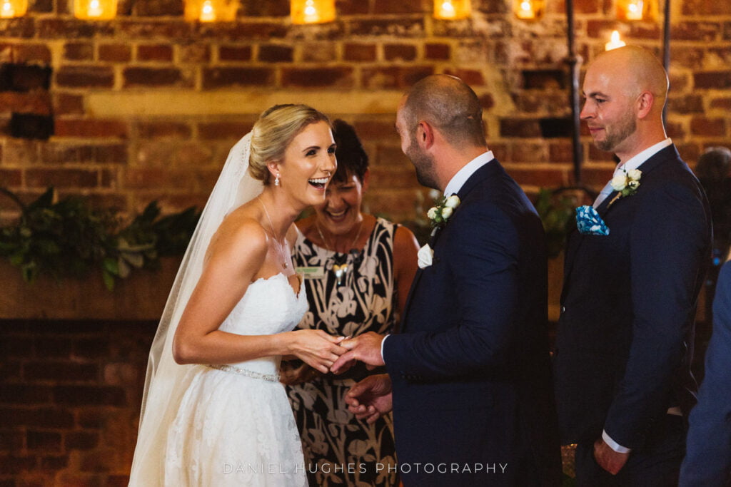 A bride laughing during the ceremony as she holds her partner's hands