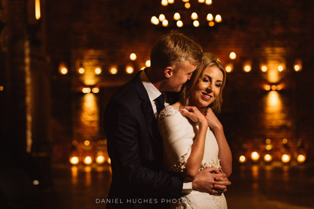 Stunning portrait of the bride and groom in the main barn at Hazel Gap, with blurry candlelight in the background 