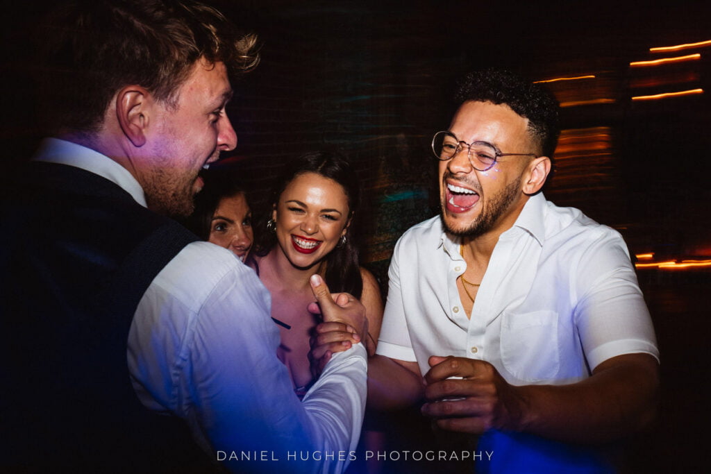 Smiling guests shaking hands on the dance floor.