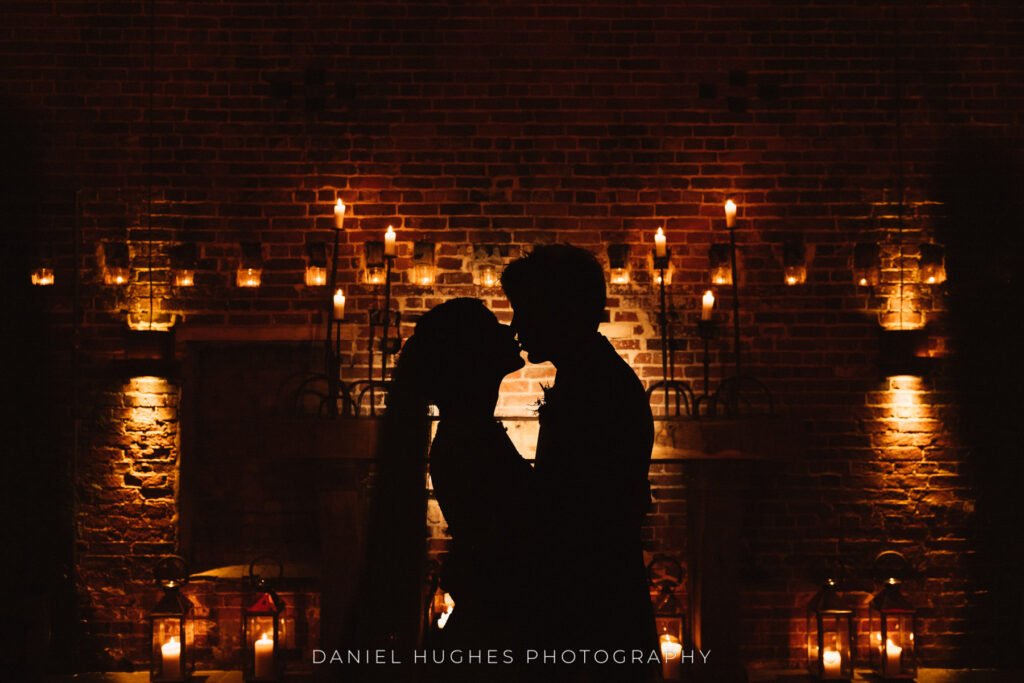 A couple silhouetted against the candlelit wall of the ceremony room at Hazel Gap